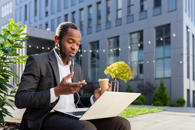 A senior african american male businessman is talking to his team via video call sitting near the