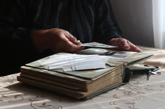 Senior-aged woman's hand holding an old photo having a fat vintage photo album in front