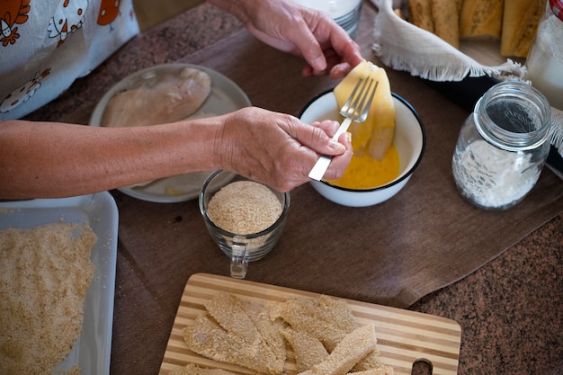 Senior alone at home cooking fish at the kitchen -  very focused indoor - mature and caucasian 60s woman - retired woman