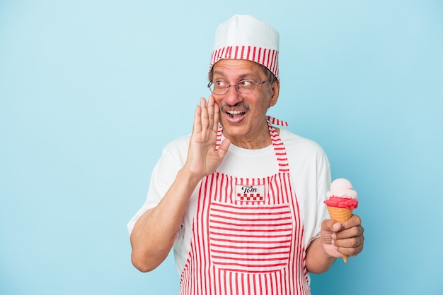 Photo senior american ice cream man holding an ice cream isolated on blue background is saying a secret hot braking news and looking aside