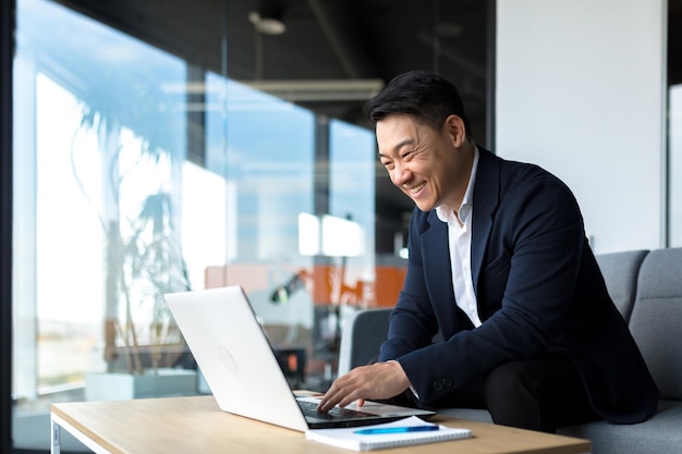 Senior Asian business man working on laptop online smiling and rejoicing happy boss business owner working in office