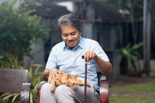 Senior asian man holding ginger cat in backyard