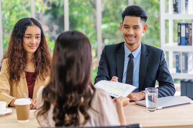 Senior Asian Manager receiving the resume document from Young Asian woman