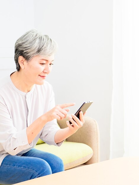 Senior asian woman holding smartphone using mobile online apps.