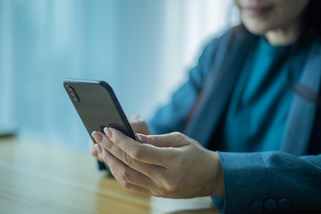 Senior asian woman using smartphone while sitting at home office