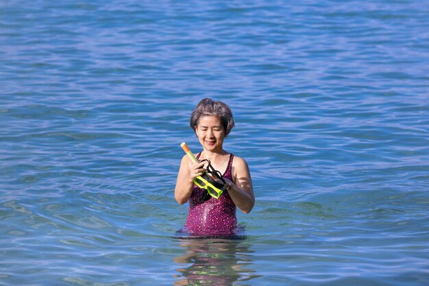 Senior asian woman with a mask for snorkeling in the sea