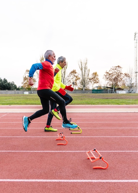 senior athletes engage in agility drills on a track field with a third in the background