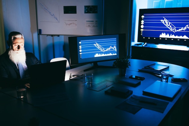 Senior business man working at night inside fintech company office  Soft focus on male face