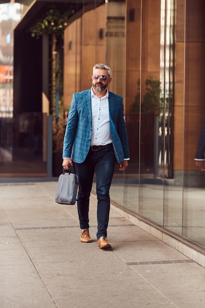 A senior businessman in a blue suit with a briefcase walking through the city.