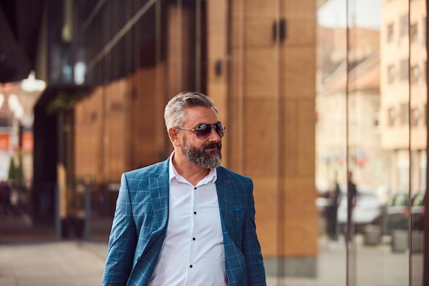 A senior businessman in a blue suit with a briefcase walking through the city.