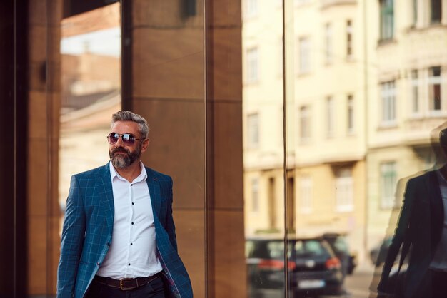 A senior businessman in a blue suit with a briefcase walking through the city.