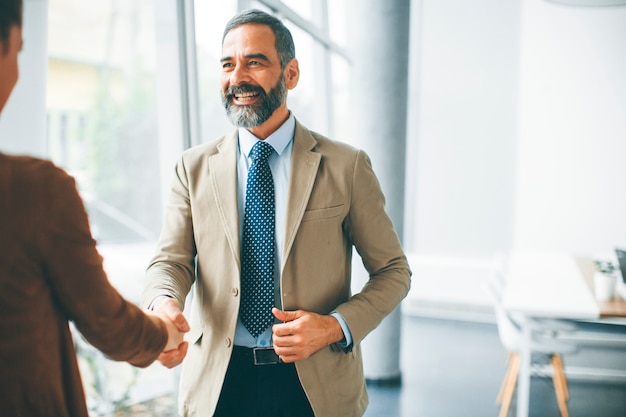 Senior businessman handshaking with young woman in the office