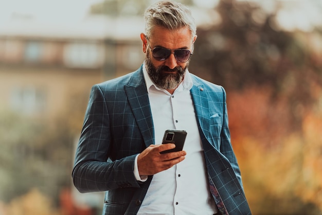 A senior businessman in a suit and sunglasses walking around the city while carrying a bag