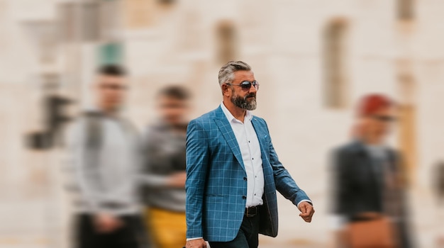 A senior businessman in a suit and sunglasses walking around the city while carrying a bag