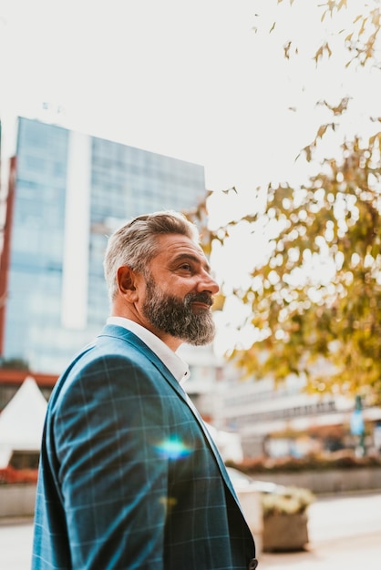 A senior businessman in a suit walking around the city after work