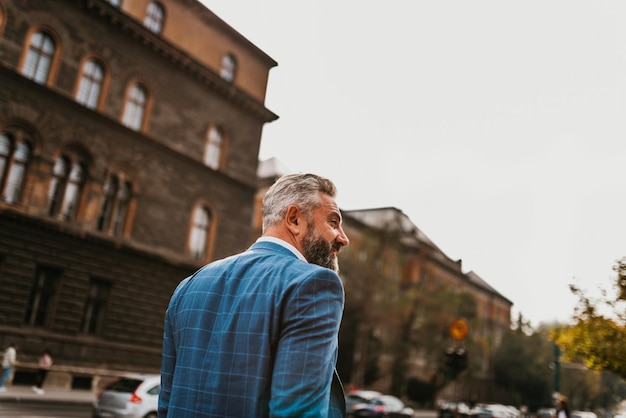 A senior businessman in a suit walking around the city after work