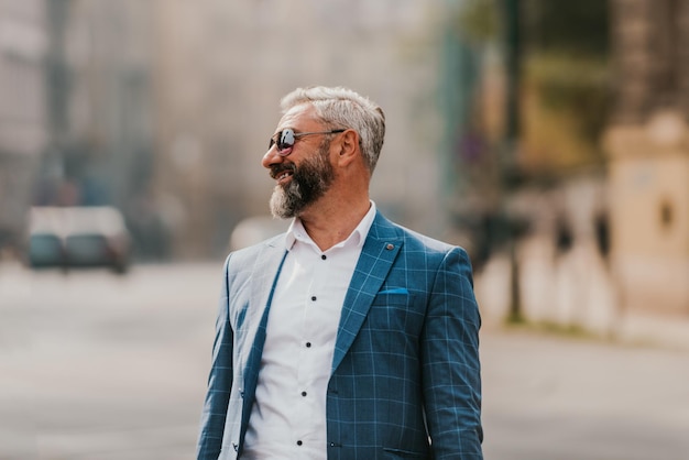 A senior businessman in a suit walking around the city after work.