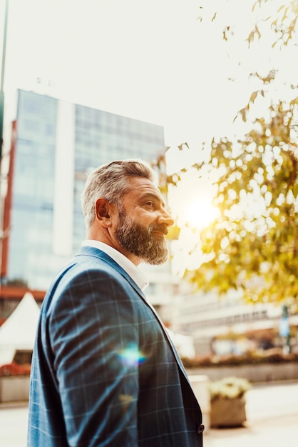 A senior businessman in a suit walking around the city after work.