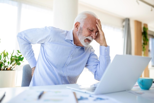 Senior businessman working sitting at desk suffers from lower back pain Damage of intervertebral discs spinal joints compression of nerve roots caused by wrong posture and sedentary work