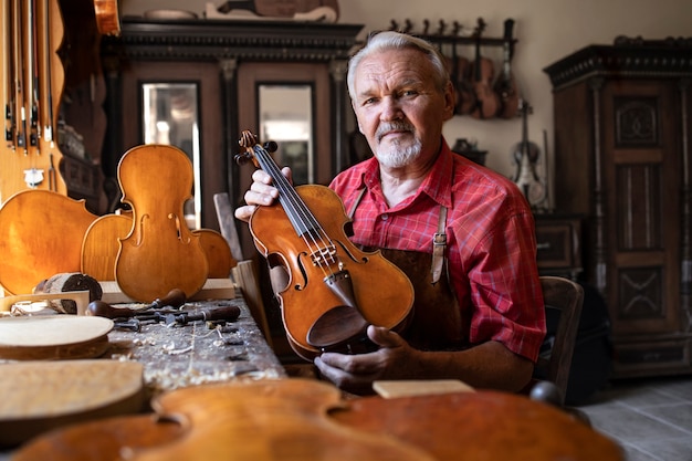 Senior carpenter showing violin instrument he created.