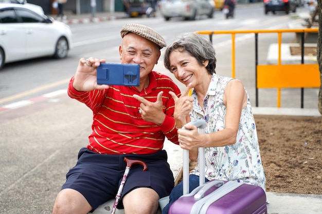 Senior Chinese tourist with his friend European poses happy and take a photo selfie