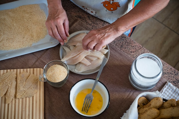 Senior cooking at home alone fish with love and passion - retired, mature and 60s woman indoor cook - hands taking fish