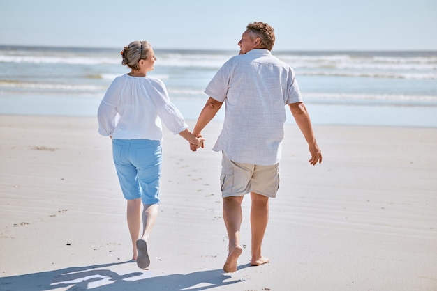 Senior couple beach and retirement vacation walking talking and happy about fitness summer and travel together Man and woman show happiness love and marriage support on nature holiday by water