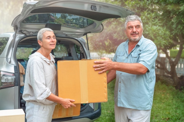 Senior couple carry box from car