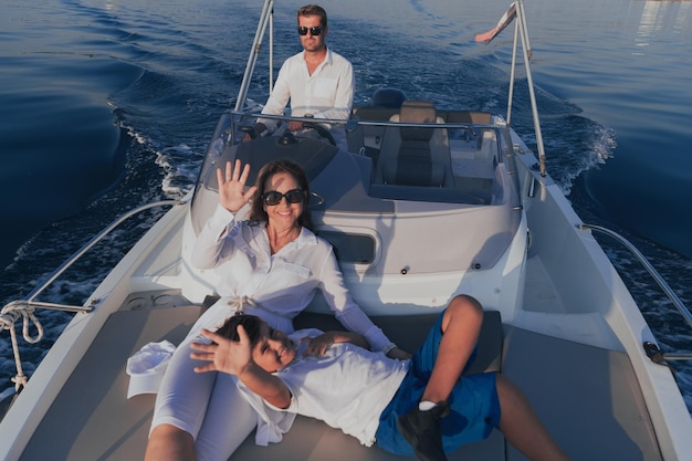 Photo a senior couple in casual outfits with their son enjoy while riding a boat at sea at sunset the concept of a happy family selective focus