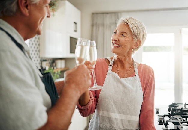 Senior couple champagne and drinks toast in house or home kitchen in marriage anniversary celebration event or retirement security success Happy smile love or elderly man woman and alcohol glass