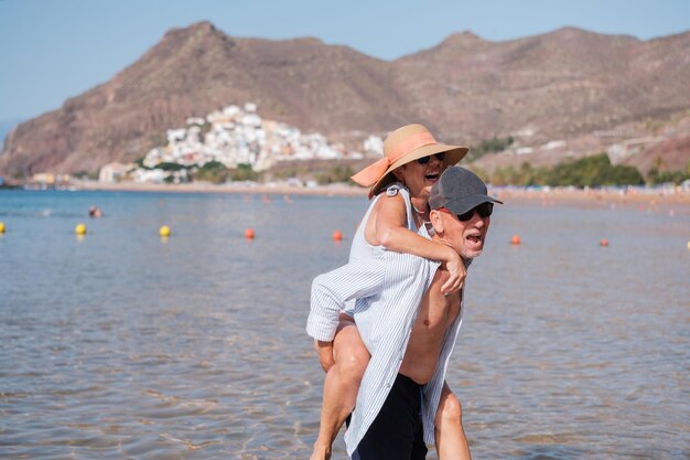 Senior couple climbing on top of each other having a fun time at the beach Concept pensioner beach fun