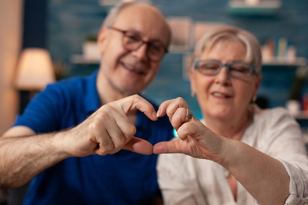 Senior couple creating heart shape figure with hands