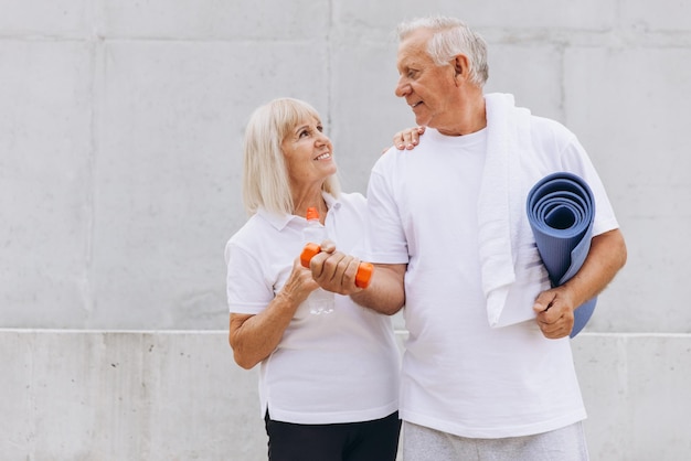 Photo senior couple enjoying fitness together with dumbbells and yoga mat outdoors