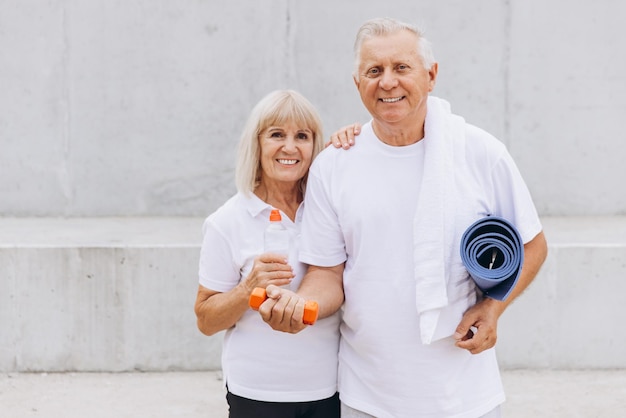 Photo senior couple enjoying fitness together with dumbbells and yoga mat outdoors