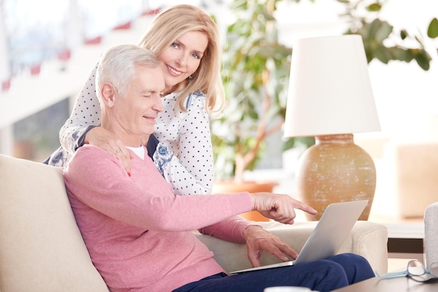 Senior couple enjoying modern technology with laptop at home