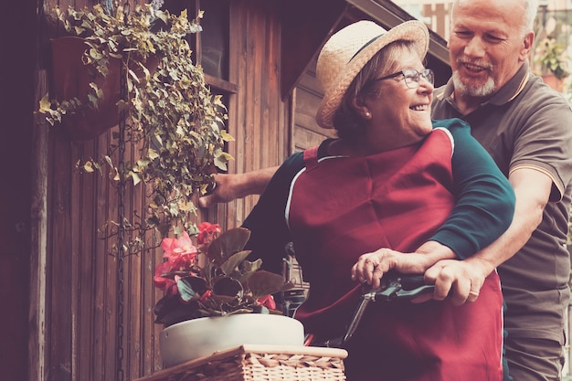 Senior couple have fun together on a bike in the garden at home.