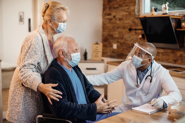 Senior couple having home visit by African American doctor during coronavirus pandemic