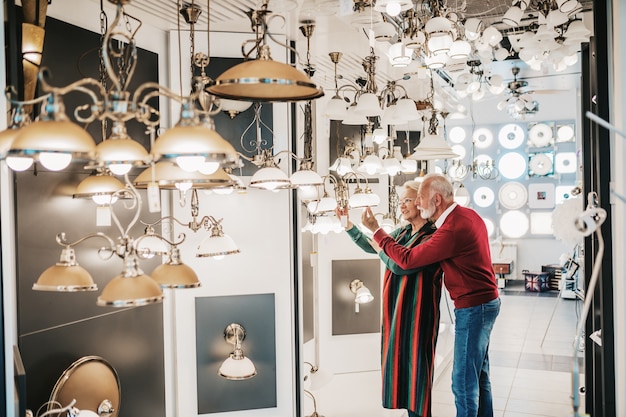 Photo senior couple in home lighting store shoosing shandelier for their home