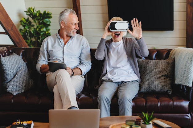 Senior couple play virtual reality glasses headset and tablet watching vr video