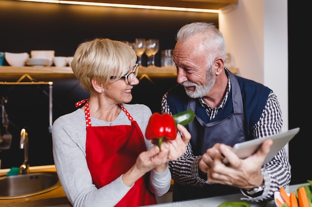 Senior couple preparing lunch together in kitchen.