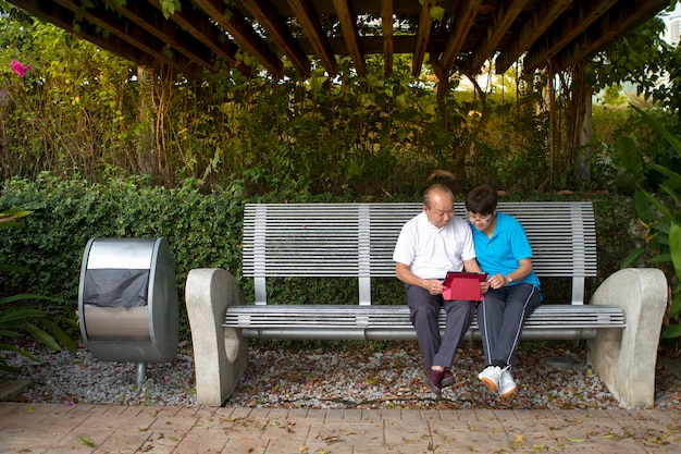 Senior couple reading a mobile tablet together in the park