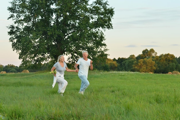 Senior couple running in field