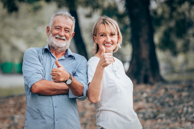 Senior couple showing thumbs up in park 