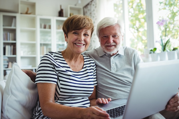 Senior couple sitting on sofa with a laptop