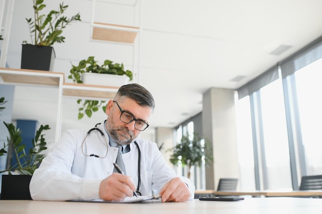 Senior doctor writing and portrait of a hospital worker in a office doing medical research Happiness laptop and checklist of a wellness and health employee with a smile from clinic vision