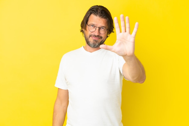 Senior dutch man isolated on yellow background counting five with fingers