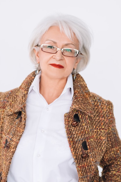 Senior fashion model portrait. Stylish elderly lady in trendy tweed outfit looking at camera.