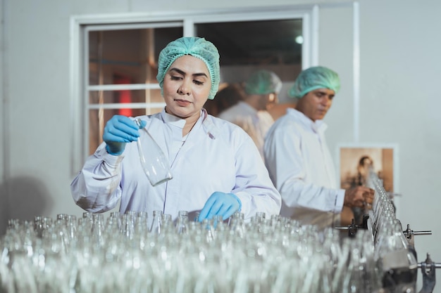 Senior female worker cleaning and check for dirt glass bottles for juice drinks in beverage factory