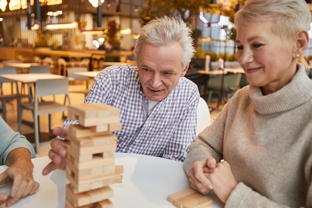 Senior friends taking block out of jenga tower