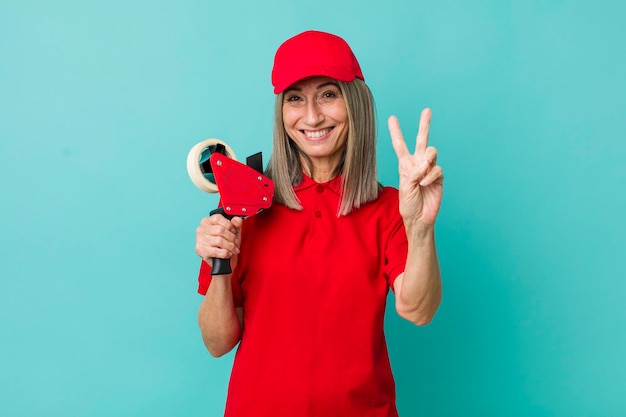 Senior gray hair woman smiling and looking friendly showing number two packer employee concept